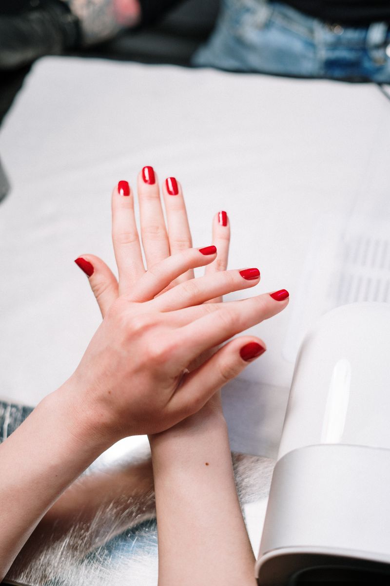 Close-up of freshly painted red gel polish on natural nails.
