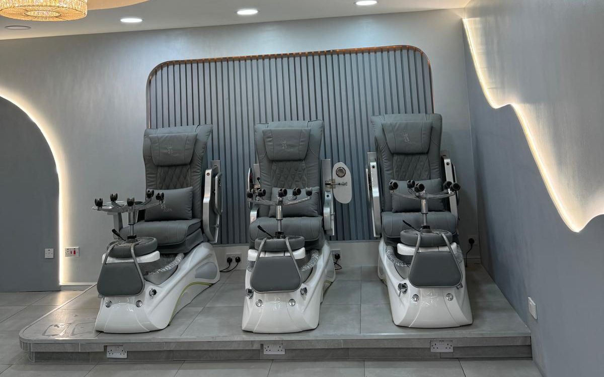 The pedicure area at Nails 4 U Great Barr — three grey spa chairs against a slatted wall with warm LED lighting.